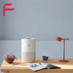 تصفیه هوای هوشمند شیائومی Smart Air Purifier 4 Compact روی میز کنار گلدان و کتاب
